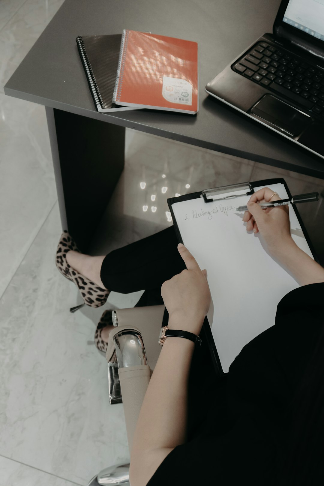 A coordinator filling out a review checklist on a clipboard at her desk