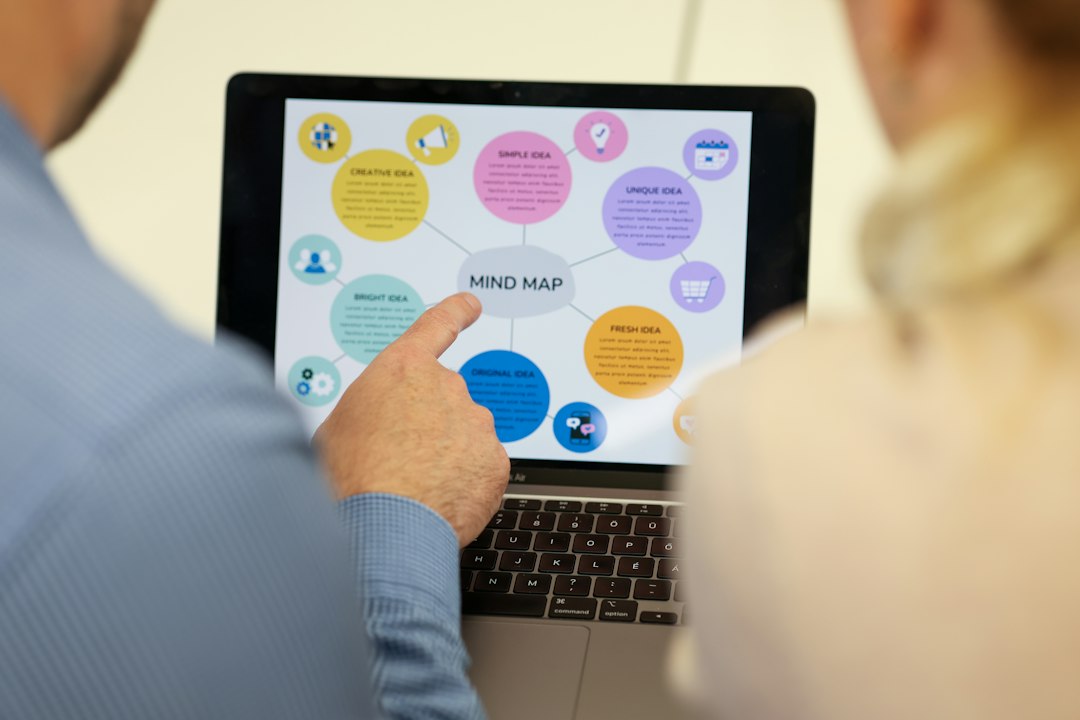 Two people comparing accreditation software frameworks displayed as a connected diagram on a laptop screen