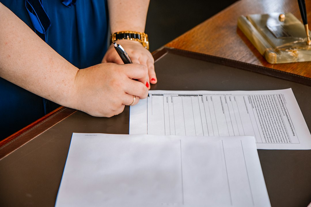 A person holding a pen over a printed document, the careful verification pass of checking whether each piece of evidence is still current