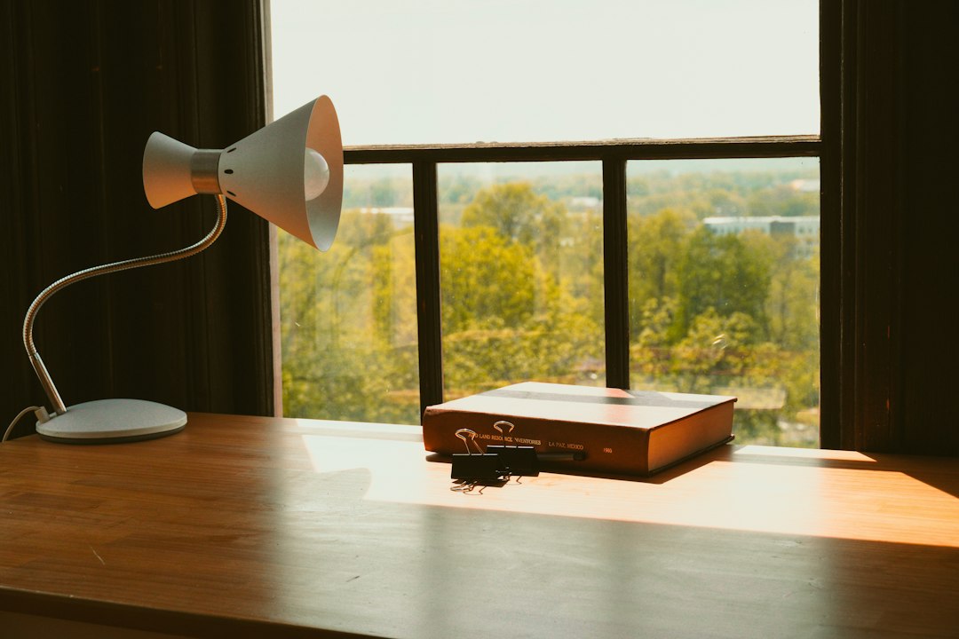 A quiet office desk with a lamp beside a window, the calm that settles over a program after the visit is over