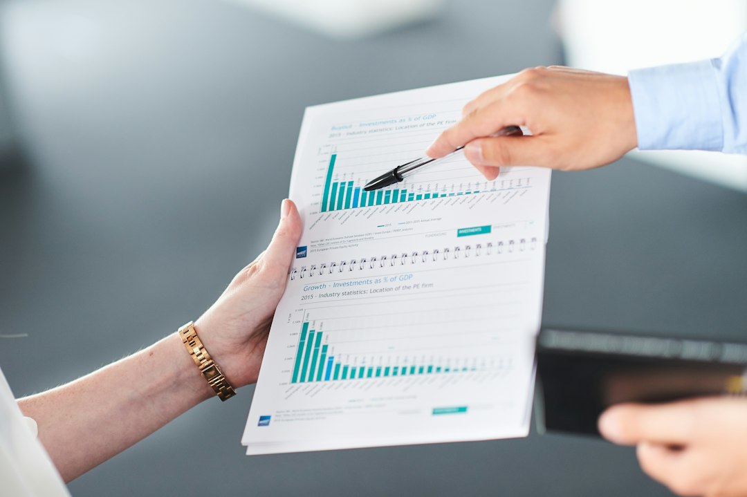 Two people examining a printed report with bar charts, the kind of CI documentation a visiting team scrutinizes for a closed loop