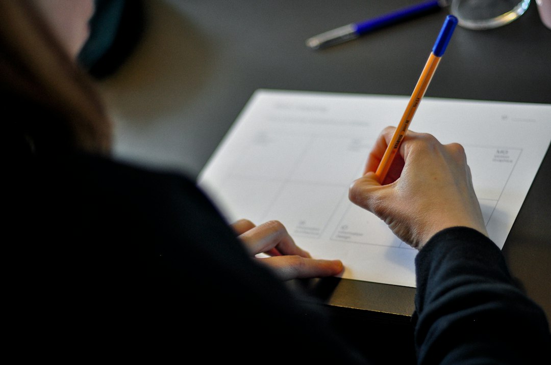 A person working through a paper form at a desk, over the shoulder