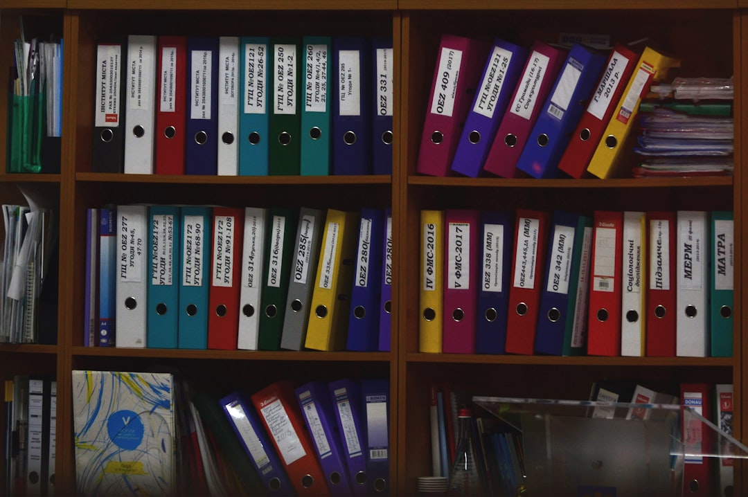 Rows of organized ring binders on office shelves, representing self-study evidence organization