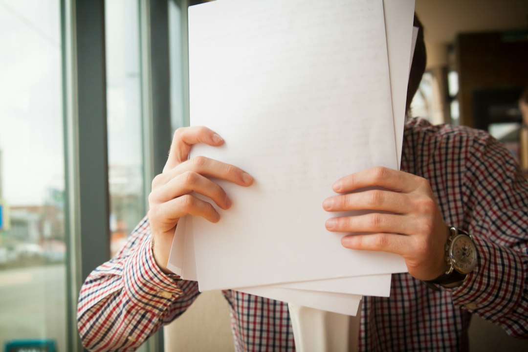 A coordinator holding a folder of program documents by a window