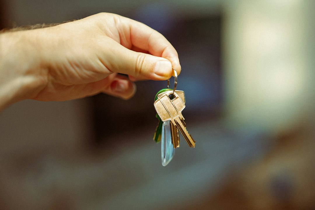 A hand holding a set of keys to a building, symbolizing the transfer of a program's sponsorship and control