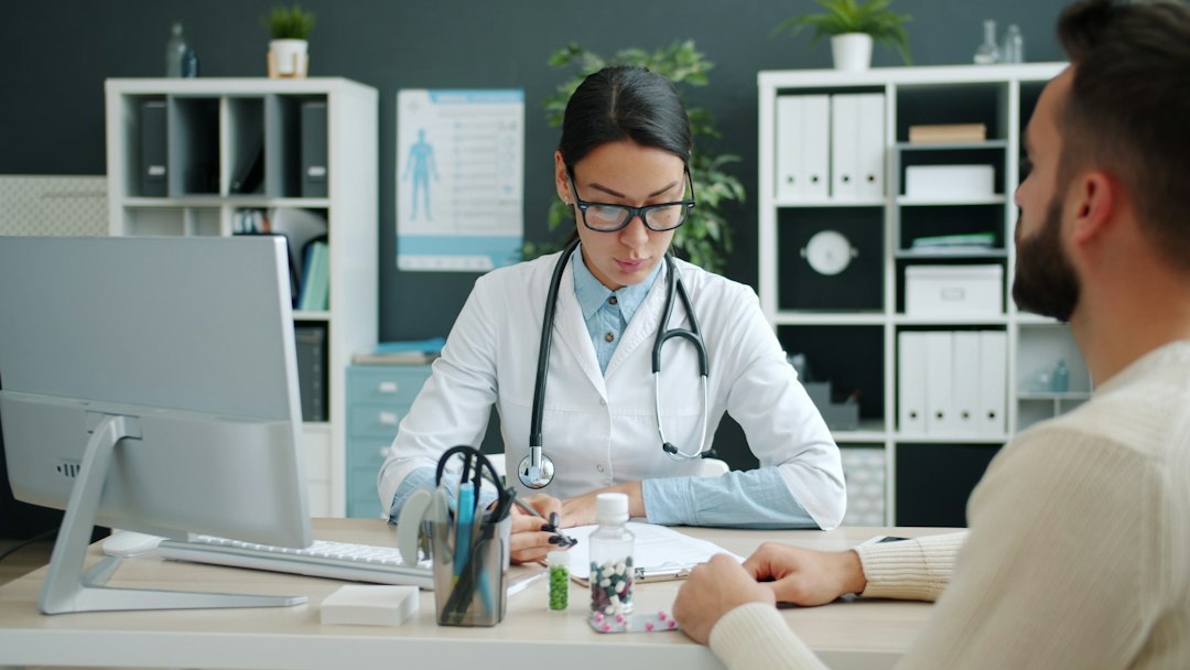 A professional in a white coat reviewing documents with a colleague at a desk