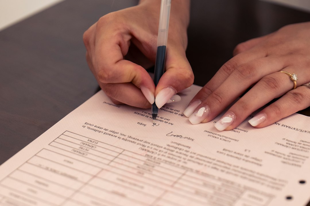 Two people reviewing a completed form, one writing and one pointing to a line