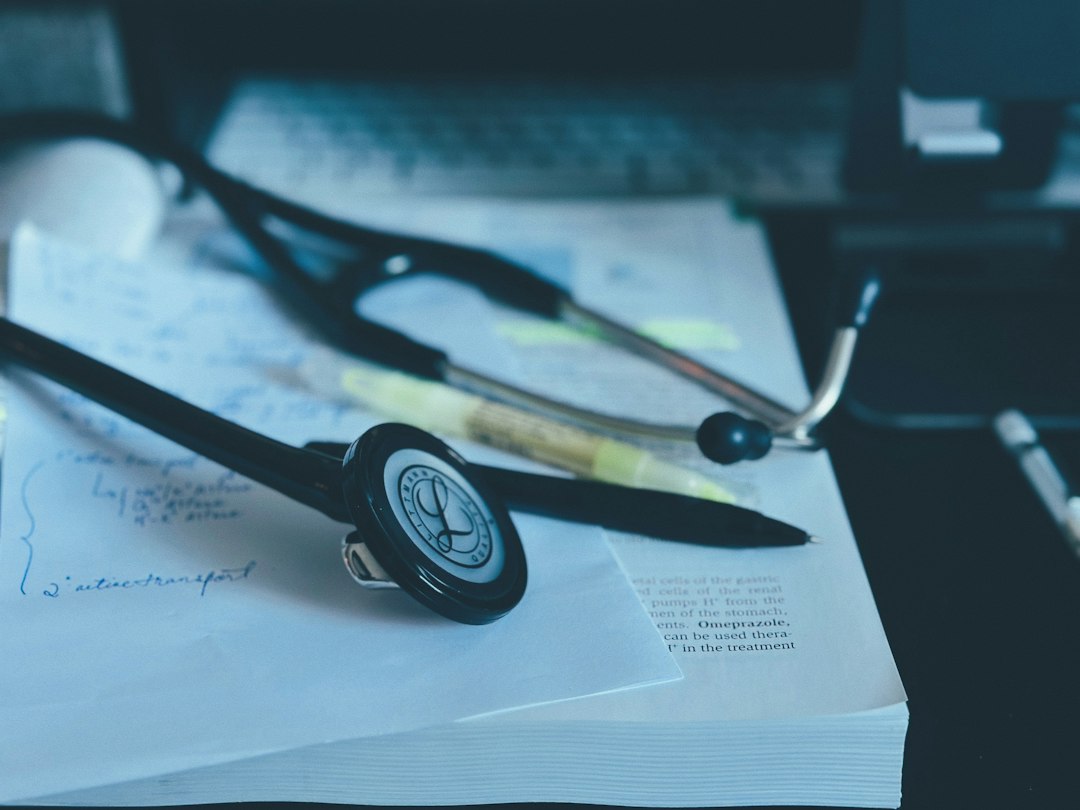 A stethoscope resting on a stack of competency records and case logs at a desk